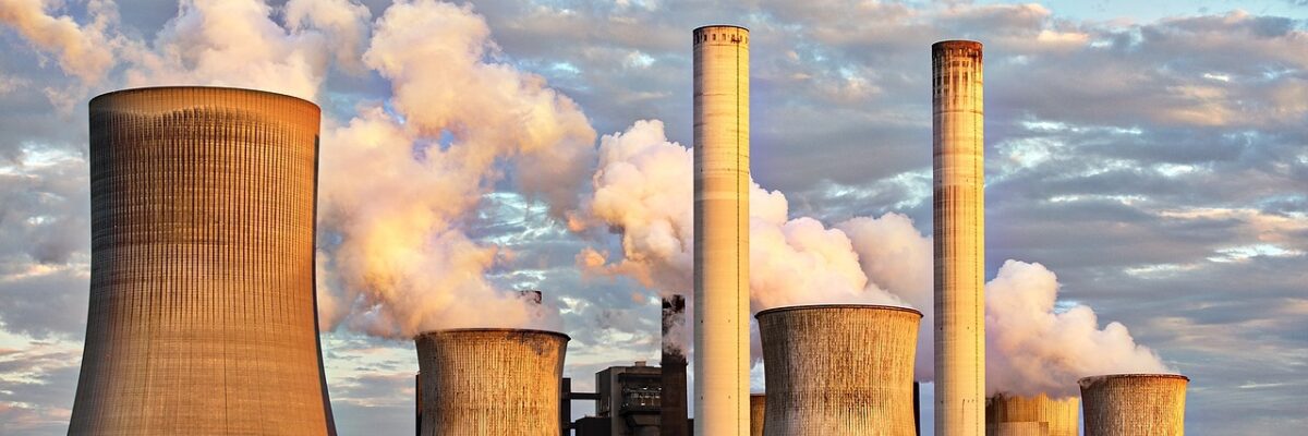 Several smoke stacks at a power plant spewing smoke into the sky.