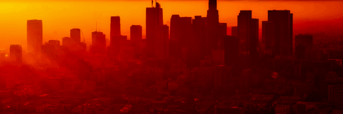 The silhouette of a skyline in front of a bright red and orange sky, obscured by smog.