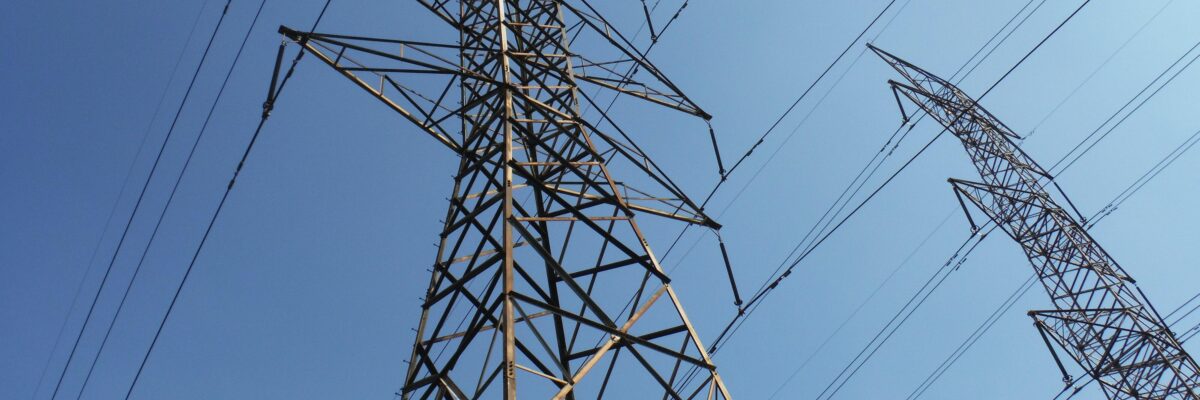 Transmission towers viewed from below; a blue sky in the background.