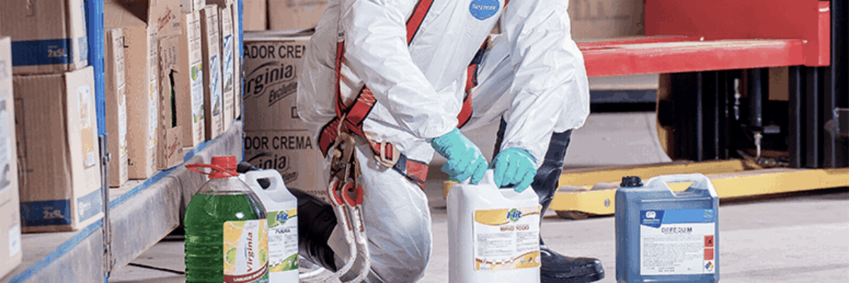 A person dressed in protective gear handling toxic substances in a warehouse.