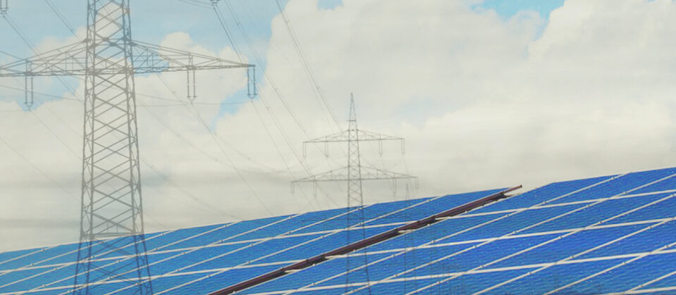 Solar panels and transmission towers; a blue sky with fluffy white clouds.