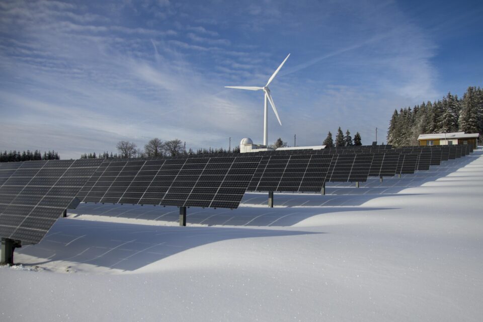 Solar panels and wind turbine on a snowy landscape
