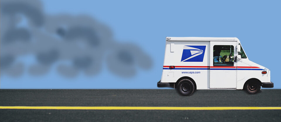 A mail truck drives down the street, releasing exhaust into a blue sky.