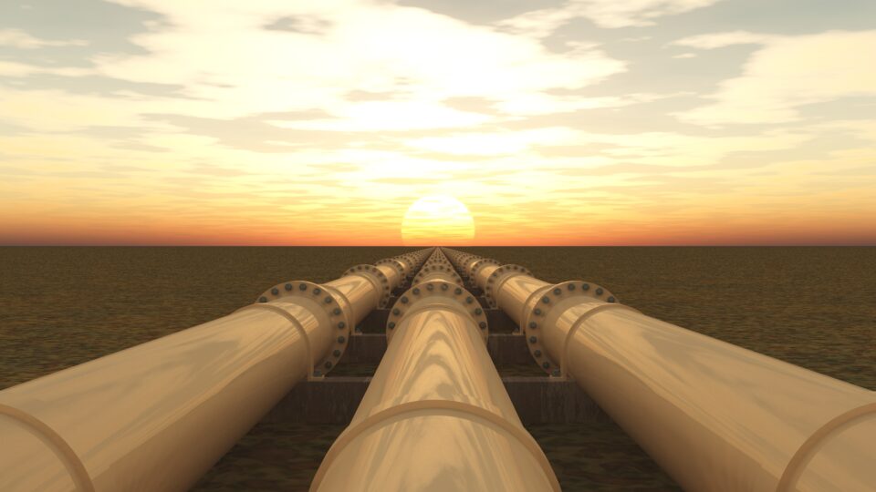 Three pipelines extend into the distance; a sunset on the horizon