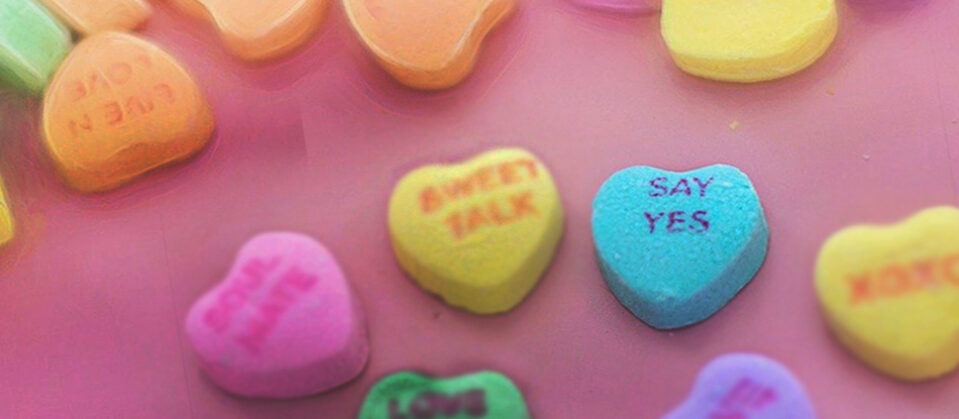 Conversation Heart candies with Pink Background; Focus on heart that says 'Say Yes'