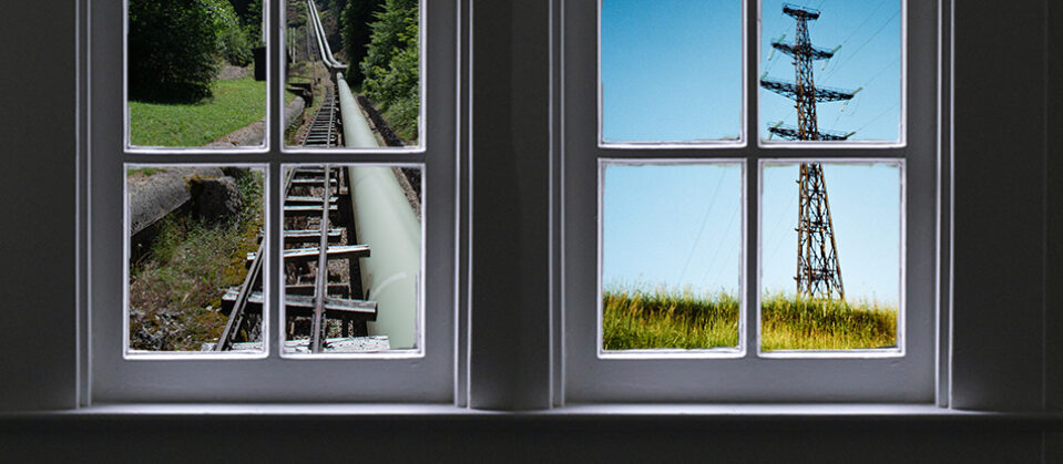 Two windows, looking out on views of a transmission tower and a pipeline.