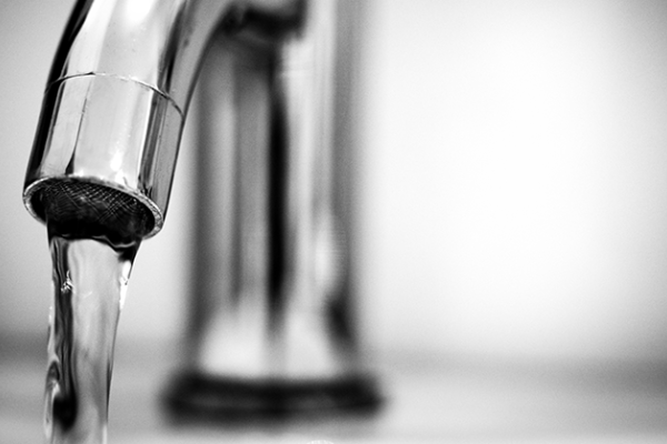 A close-up view of a silver water faucet with clear water streaming out of it.