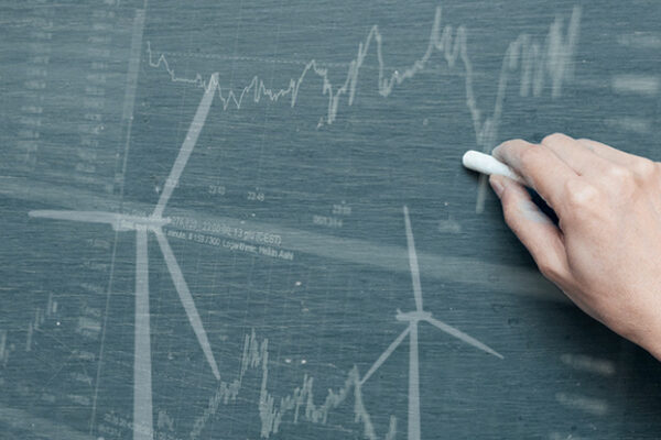 A hand drawing offshore wind turbines and line graphs on a chalk board.