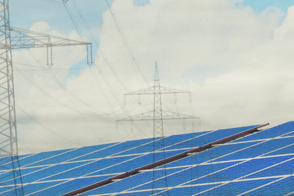 Solar panels and transmission towers; a blue sky with fluffy white clouds.