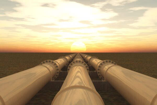 Three pipelines extend into the distance; a sunset on the horizon