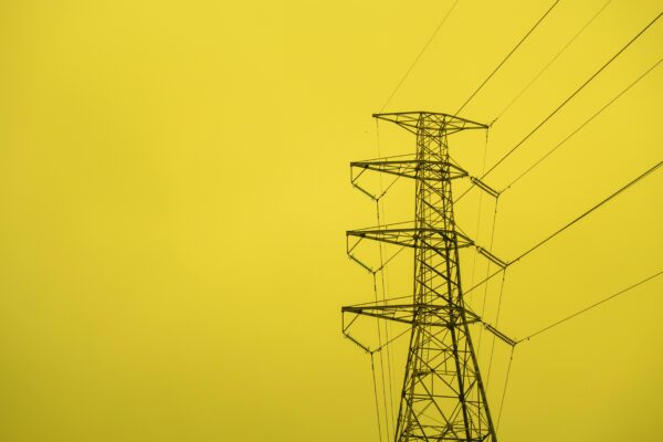An inky black transmission tower against a bright yellow sky