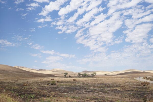 An arid landscape with a blue sky and clouds.