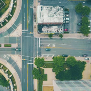 An aerial view of an intersection, with green trees on the corners.