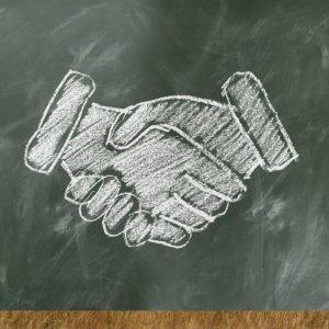 A chalk drawing of a handshake on a green chalk board; the State Impact Center logo in the corner