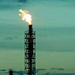 Methane flaring in front of a turquoise twilight sky.