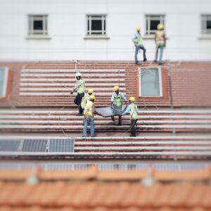 Construction workers installing solar panels on a building, viewed from a distance